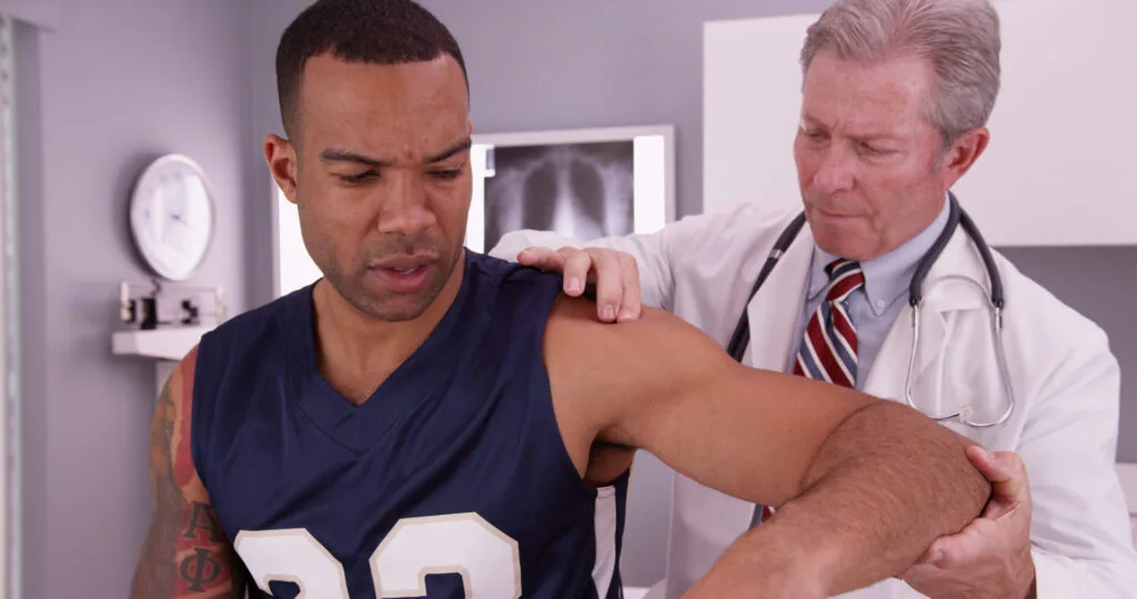 Doctor examining patient's shoulder in medical office