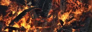 Intense orange and yellow flames consuming dark charred wood logs