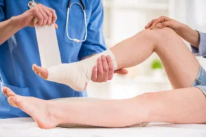 Healthcare provider wrapping white bandage around patient's ankle and foot